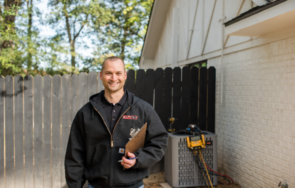 Texas Bree technician holding installation paperwork after completing a new outdoor condenser installation