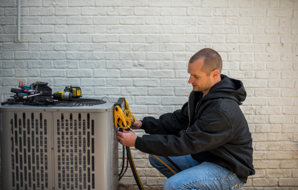 HVAC technician verifying refrigerant pressures with gauges at an outdoor condenser